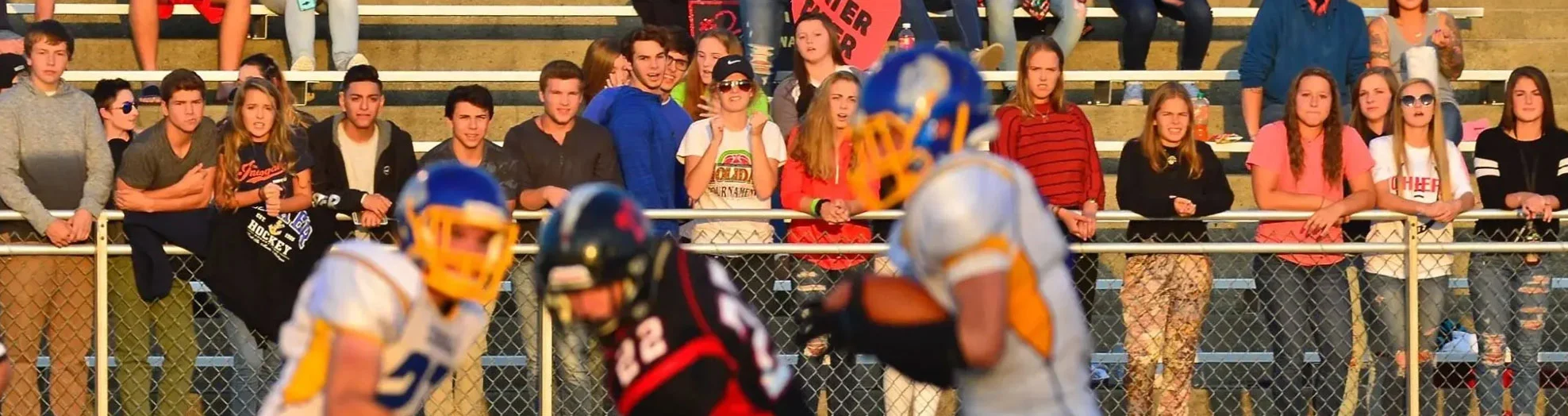 Spectators watch a high school football game from the bleachers.